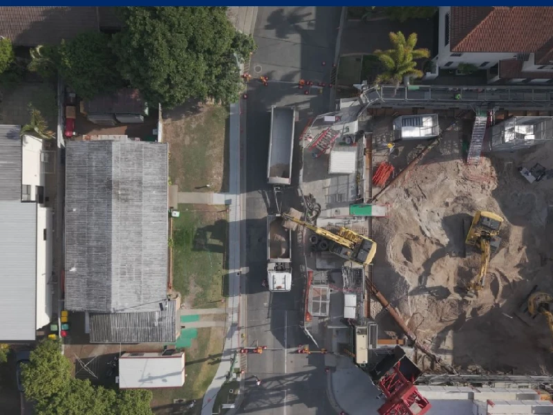 Aerial view of roadwork construction site with traffic management setup, excavation equipment, and roadside operations