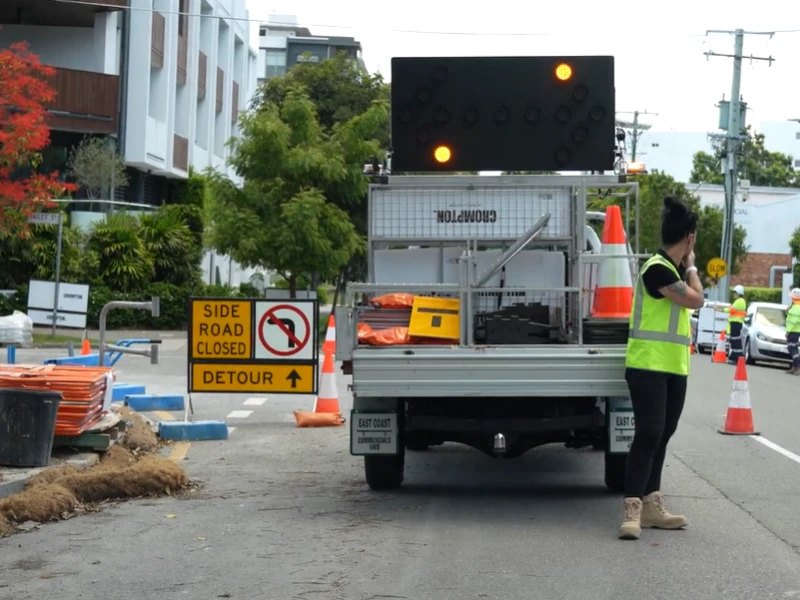 VMS board and traffic control vehicle positioned beside roadside detour and road closure signage