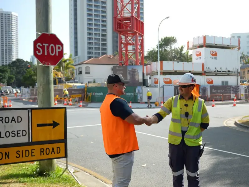 Traffic management personnel coordinating roadside operations with site briefing during active roadwork project